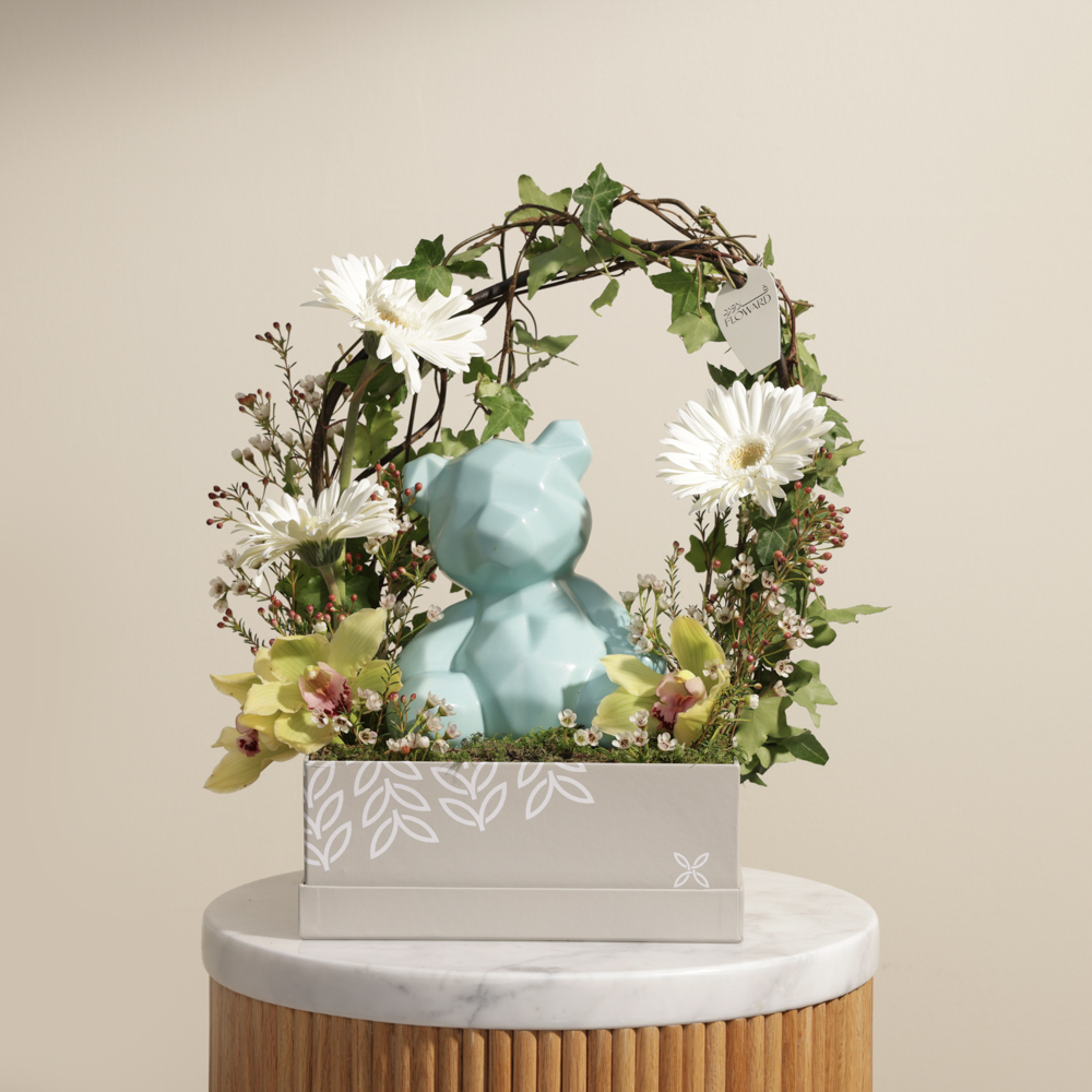 دب أزرق مع زهور بيضاء وخضراء
